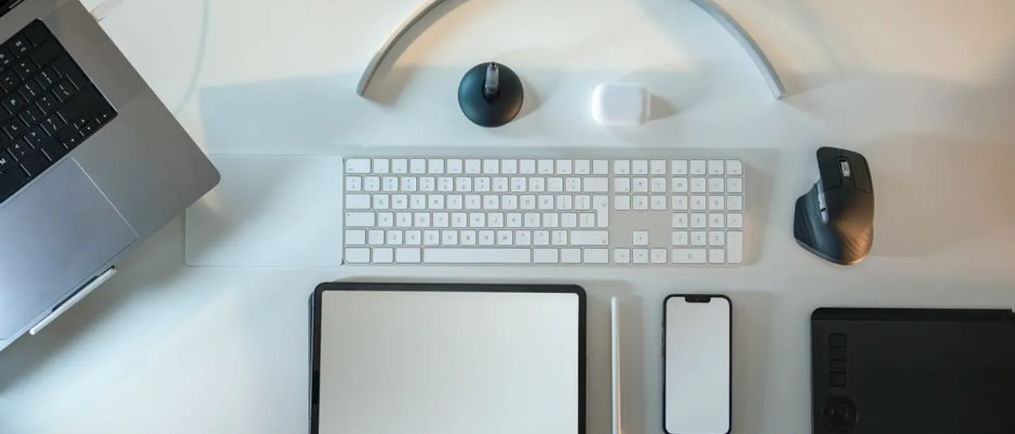 A designer's desk with a laptop, tablet, and drawing pad
