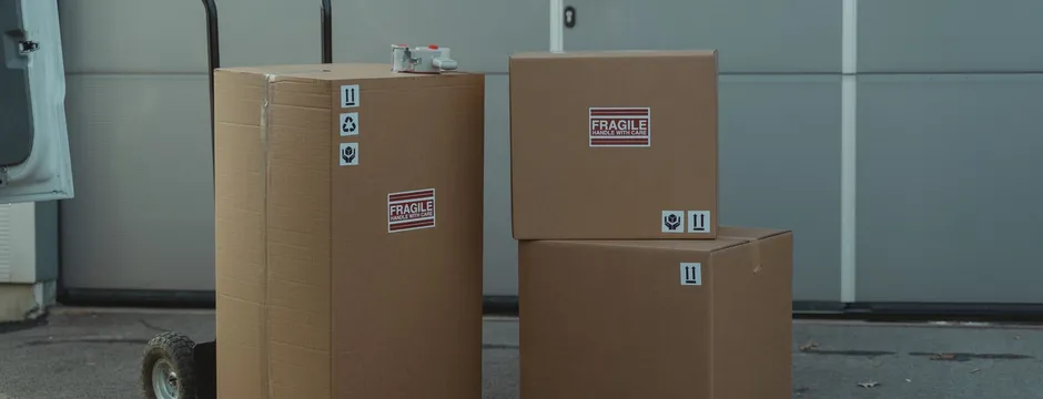 Packed shipping boxes marked Fragile on a hand truck